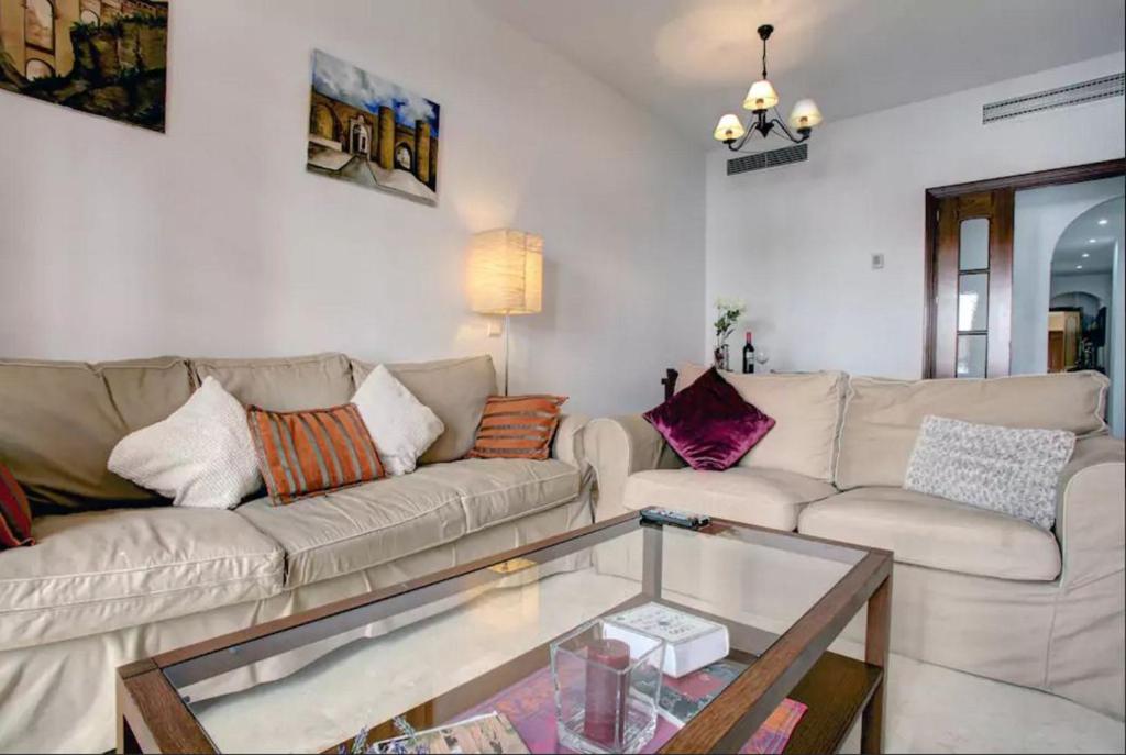 uma sala de estar com um sofá e uma mesa de vidro em Apartamento Atenea centro con garaje gratuito em Ronda