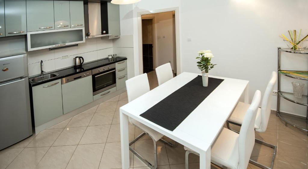 a kitchen with a white table and white chairs at Žnjan Beach Apartments in Split