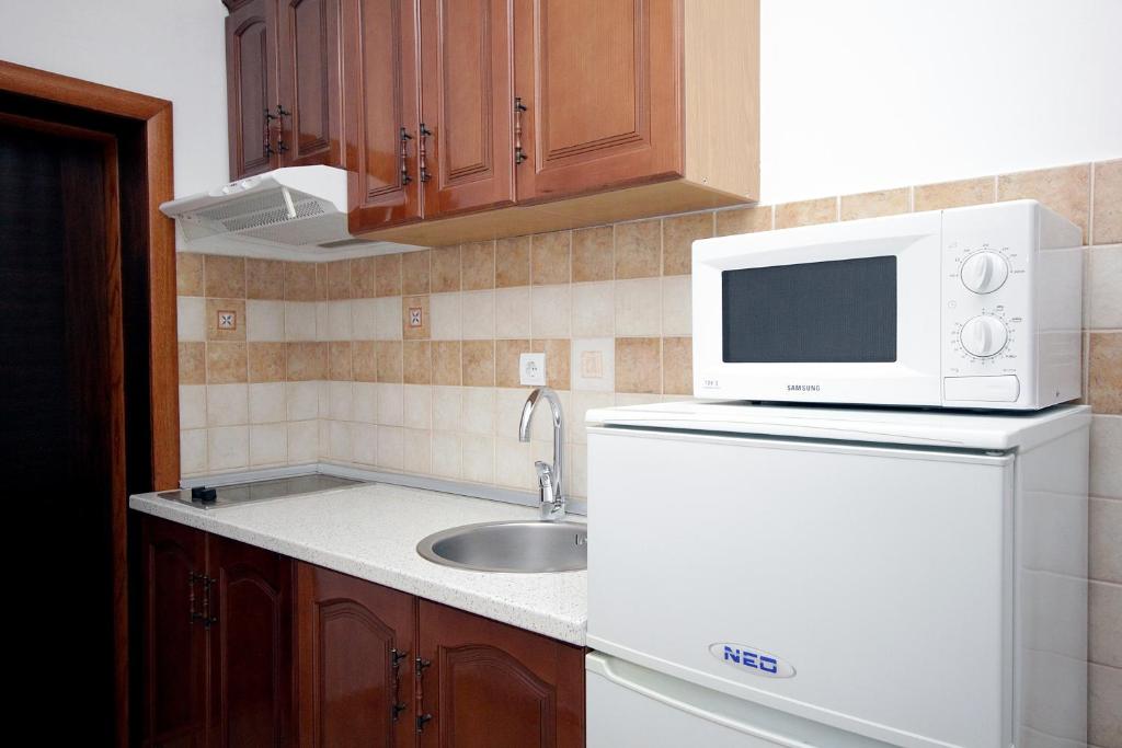 a kitchen with a white microwave and a sink at Apartmani More in Sveti Stefan