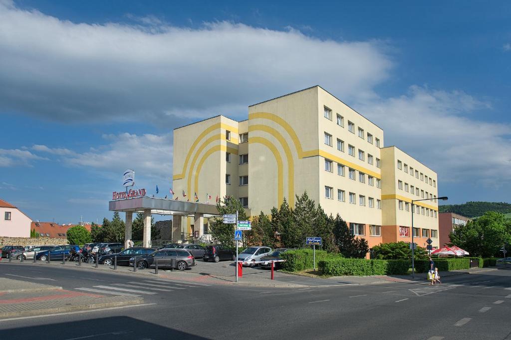a large building with a parking lot in front of it at Hotel Grand Litava Beroun in Beroun