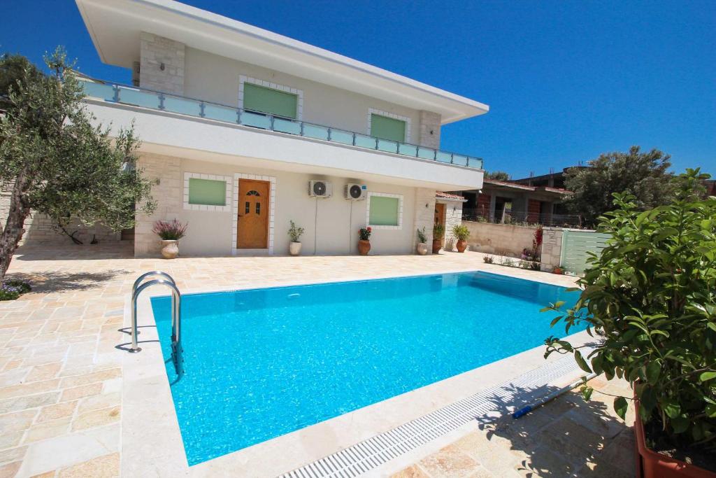 une villa avec une piscine en face d'une maison dans l'établissement Villa Aleandro, à Ksamil