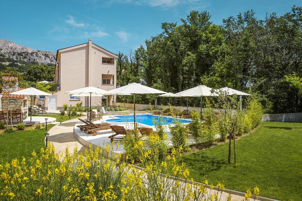un jardin avec une piscine et des parasols et un bâtiment dans l'établissement Residence Mediterraneo, à Baška