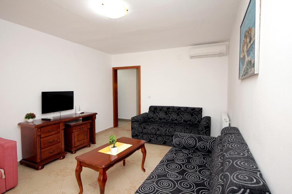 a living room with a couch and a tv at Apartmani More in Sveti Stefan