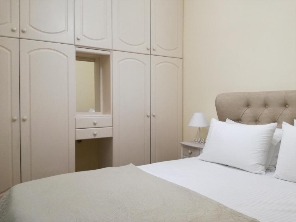 ein weißes Schlafzimmer mit einem weißen Bett und weißen Schränken in der Unterkunft Thiseio Home in Athen