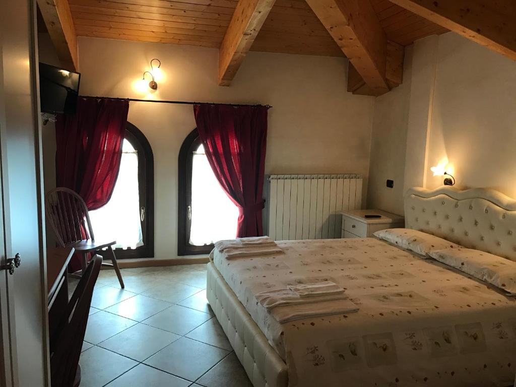 1 dormitorio con 2 camas y 2 ventanas en Locanda La Posta Nöa, en Vezza d'Oglio