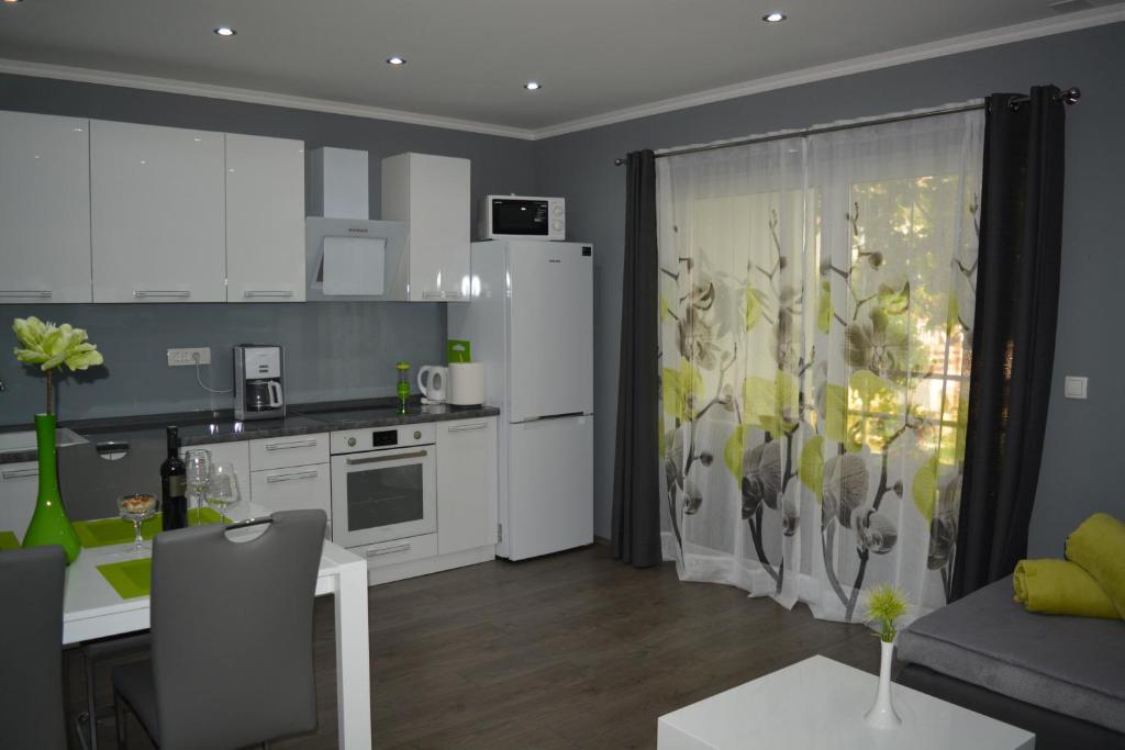 uma cozinha e sala de estar com armários brancos e uma mesa em Apartment D & N em Kaštela