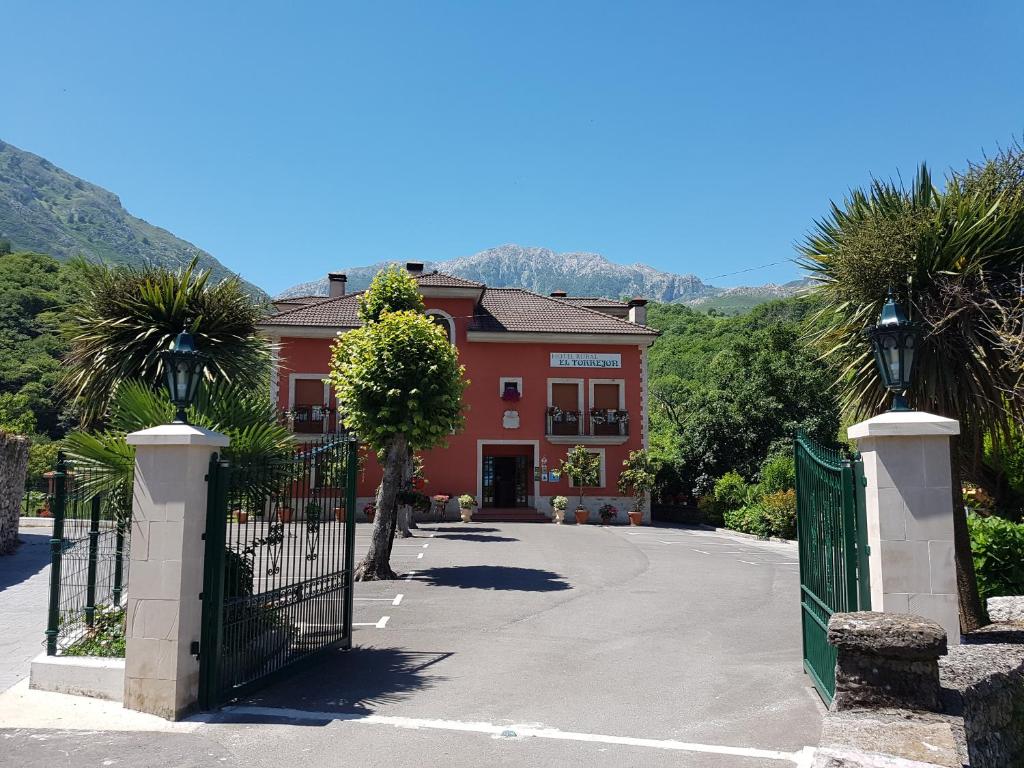 un bâtiment rouge avec un portail et des palmiers dans l'établissement Hotel Rural El Torrejon, à Arenas de Cabrales