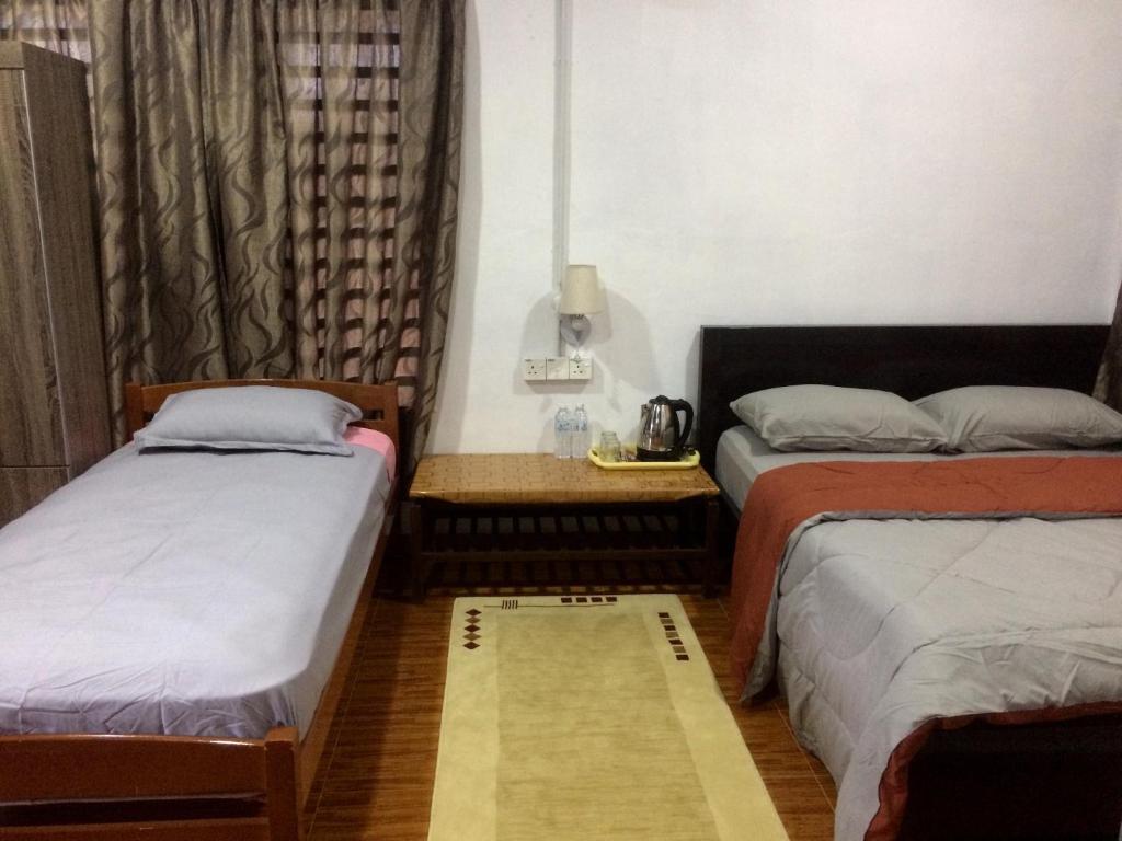 a room with two beds and a table in it at Roomstay Zulmi in Arau