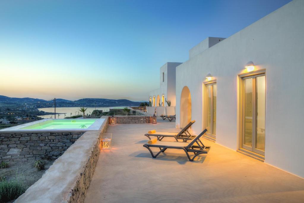 a patio with two chairs and a table next to a building at Natura Villas Paros in Molos Parou