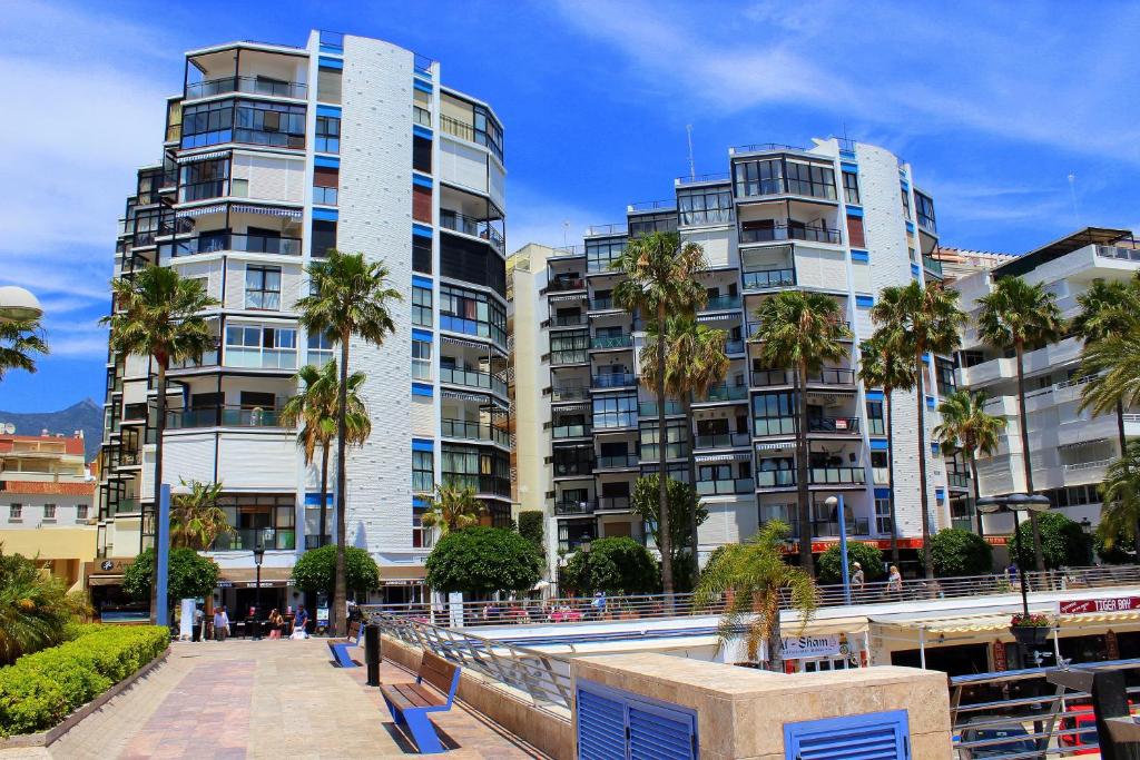 een rij hoge gebouwen met palmbomen voor de deur bij Estudio Puerto Deportivo Marbella in Marbella