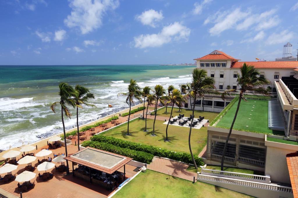 a beach scene with a beach house and a large body of water at Galle Face Hotel in Colombo