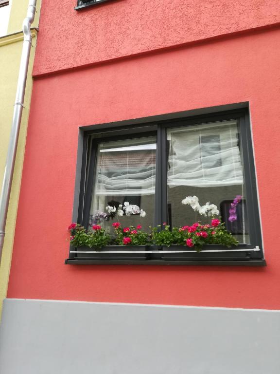 a red building with a window with flowers in it at Ferienwohnung Amalie in Apolda