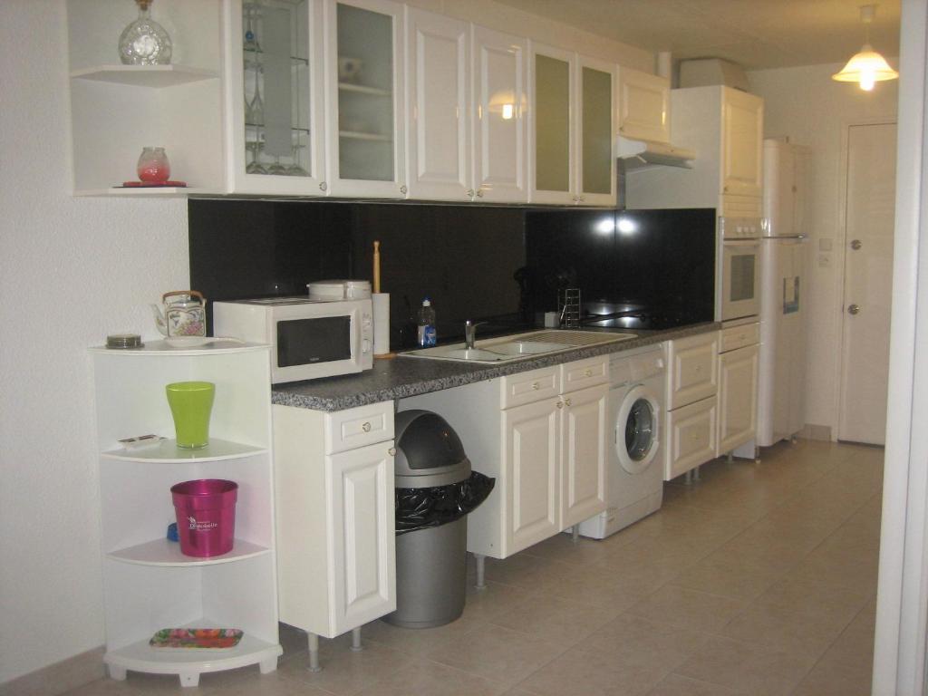 a kitchen with white cabinets and a sink and a microwave at Studio 27 Orient Bay in Orient Bay