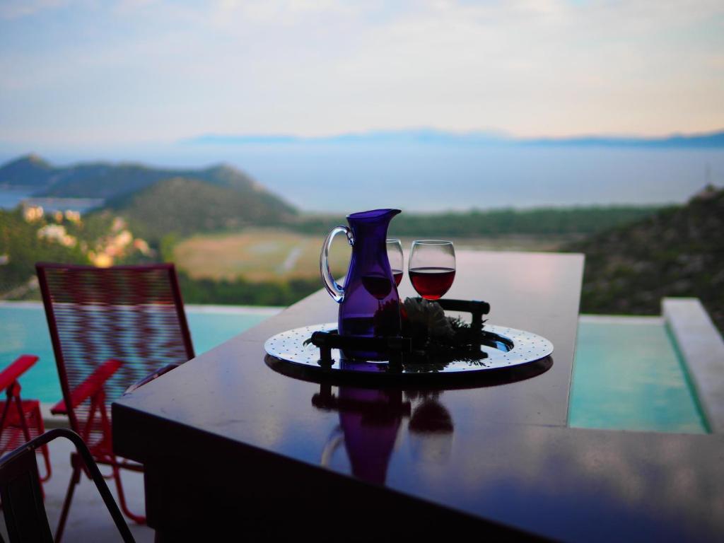 a table with a glass of red wine and a pitcher at Red Grey Sea View Villa in Schinias