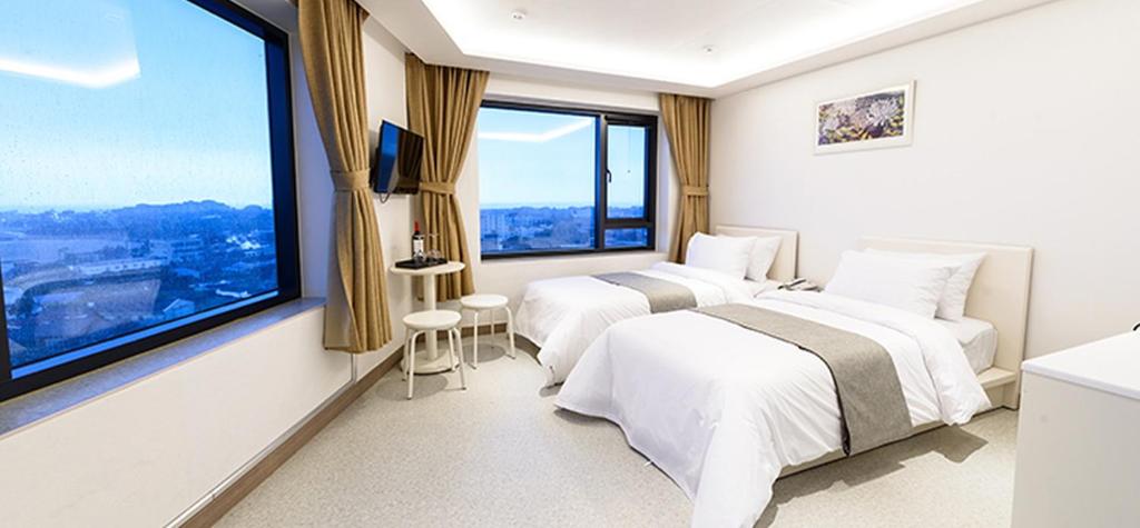 a hotel room with two beds and a large window at Rezion Hotel in Seogwipo