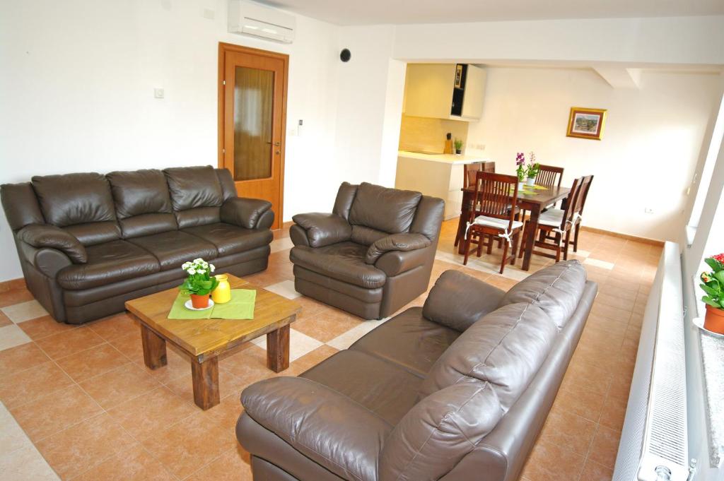 a living room with a leather couch and a table at Braće Ilić 1 in Fažana