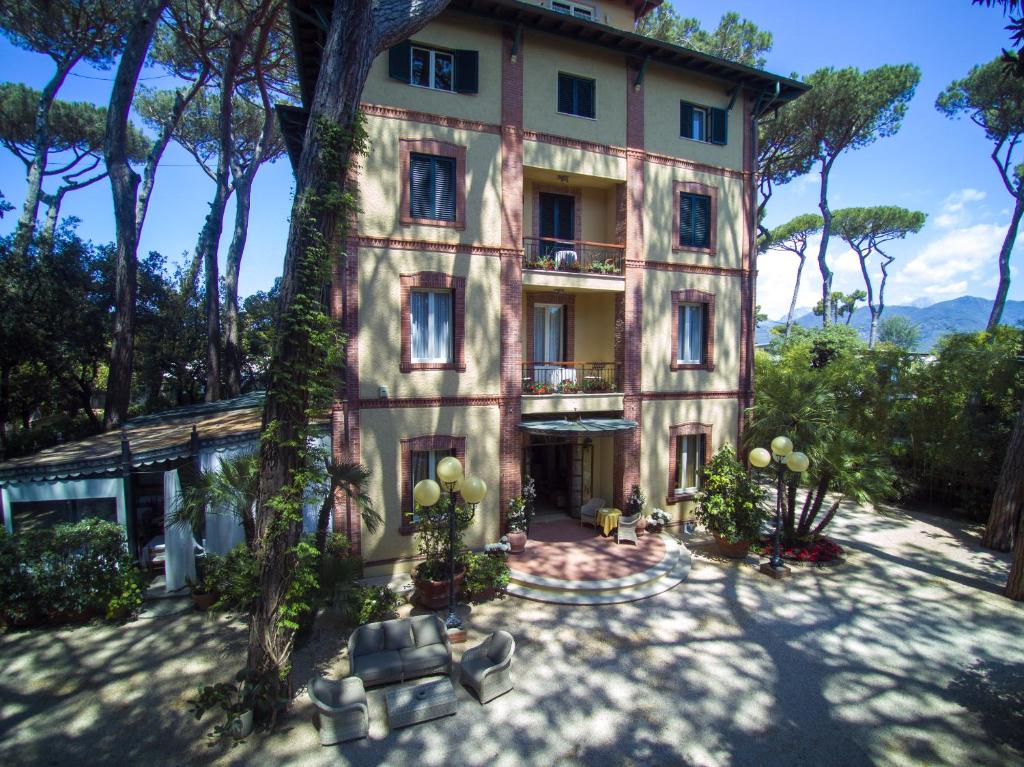 un grande edificio con alberi di fronte di Hotel Villa Tiziana a Marina di Pietrasanta