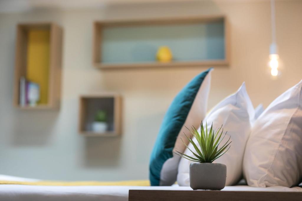 a couch with pillows and a potted plant on it at Hotel Nap By HappyCulture in Nice