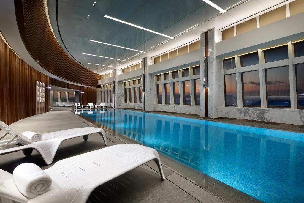 a swimming pool in a hotel with two beds and chairs at Signiel Seoul in Seoul