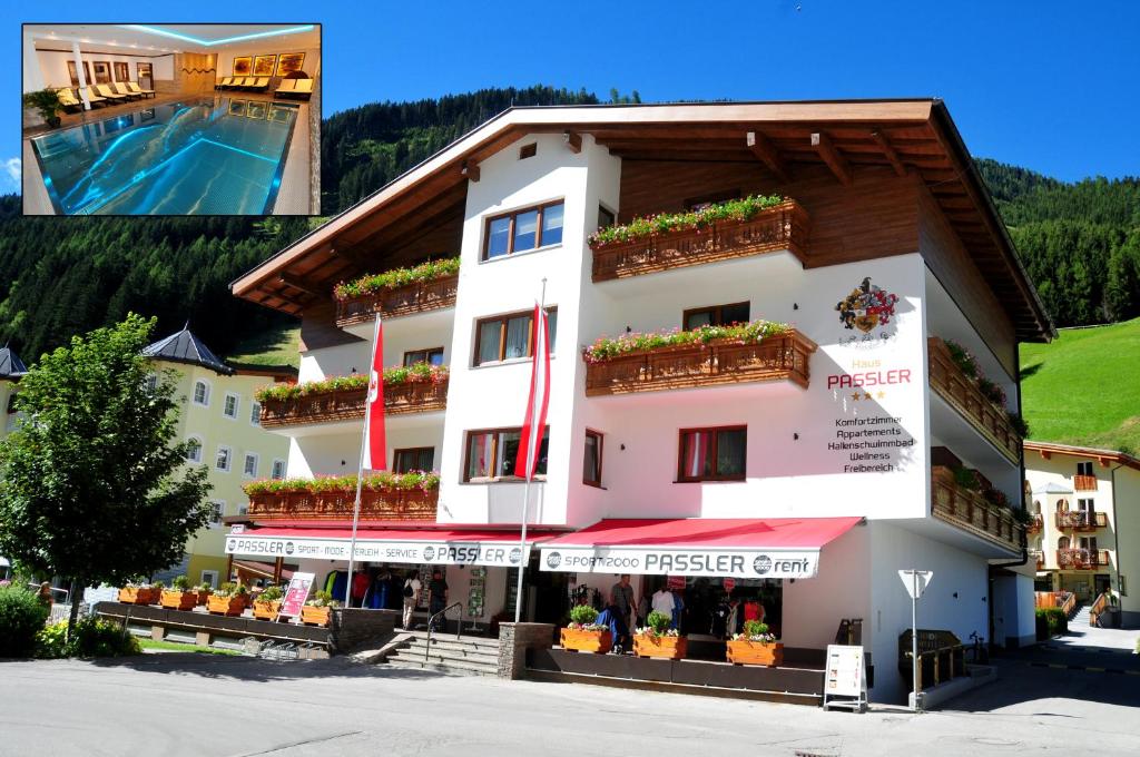 ein großes weißes Gebäude mit Blumen auf den Balkonen in der Unterkunft Haus Passler in Sankt Jakob in Defereggen