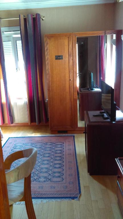 a living room with a chair and a desk and a television at Hotel de l&#39;Orangerie in Strasbourg