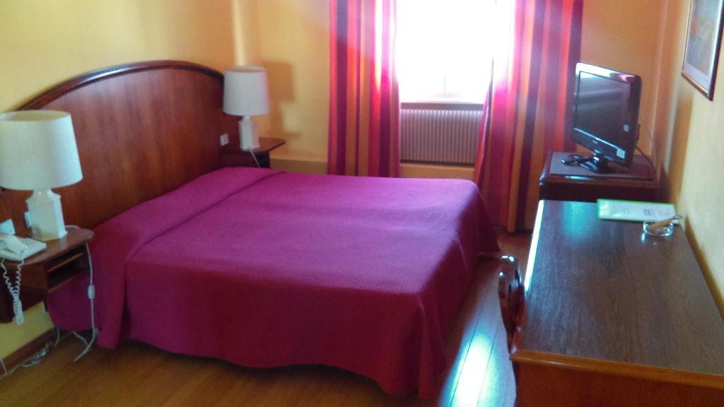 a bedroom with a purple bed and a television at Hotel de l&#39;Orangerie in Strasbourg