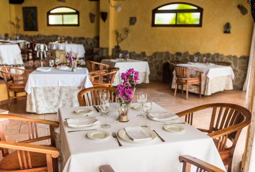 a dining room with white tables and chairs with flowers at El Cortijo de Zahara by QHotels in Zahara de los Atunes