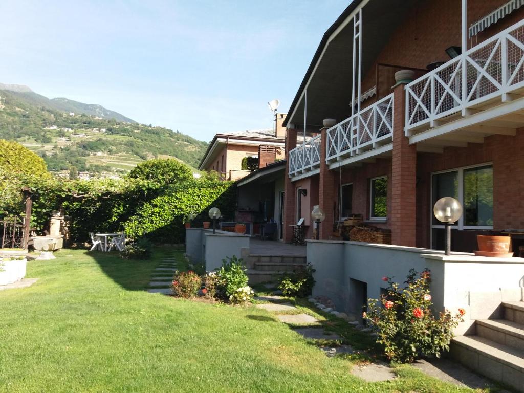 une maison avec une cour herbeuse devant elle dans l'établissement Casa Lumiere, à Aoste