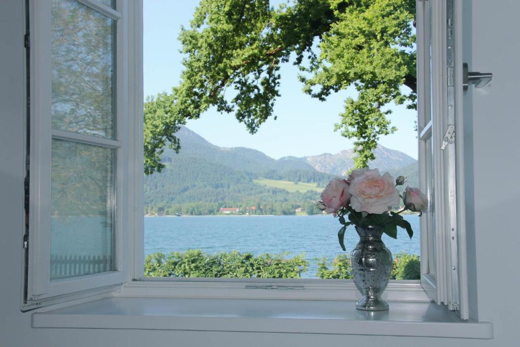 um vaso com flores cor-de-rosa sentado no peitoril da janela em Palace am See em Tegernsee