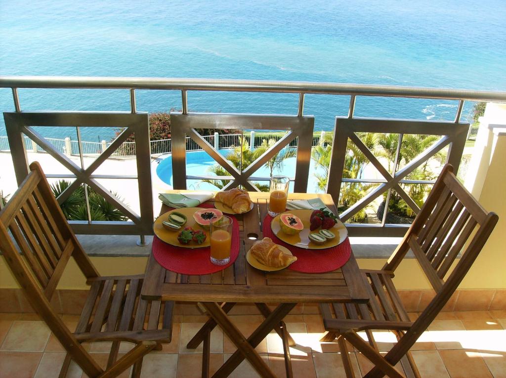 フンシャルにあるOceanfront Apartmentの海を望むバルコニーの上にテーブルと食べ物
