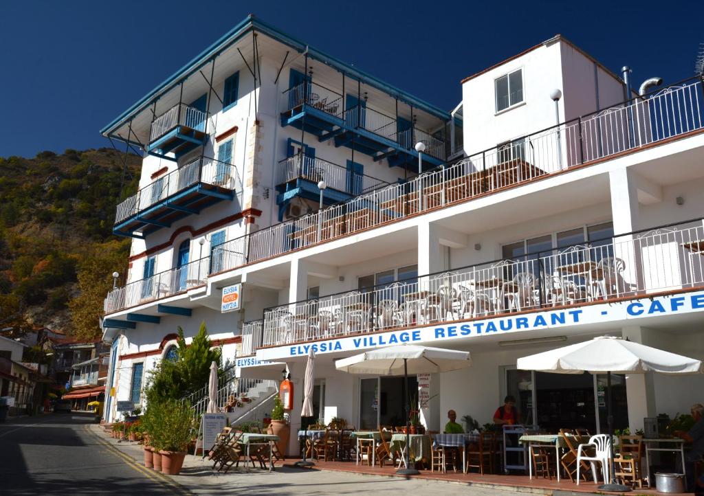 a white building with tables and chairs in front of it at Elyssia Hotel in Pedoulas