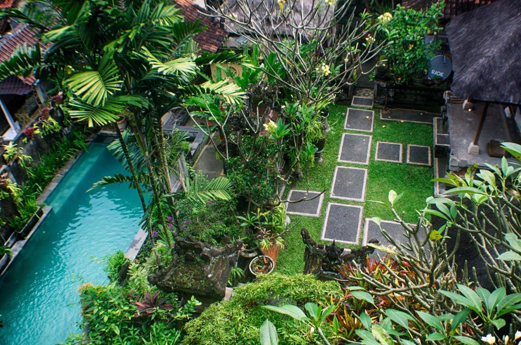 einen Garten mit einem Pool mit Bäumen und Pflanzen in der Unterkunft Rumah Roda in Ubud