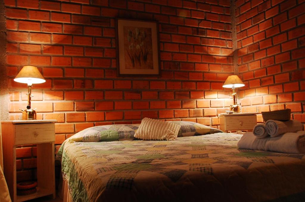 a bedroom with a brick wall with a bed and two lamps at Posada del Bosque in Rivera