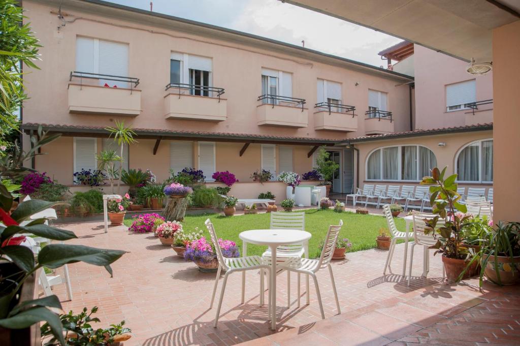 une cour avec des chaises et une table en face d'un bâtiment dans l'établissement Hotel Sabrina, à Castiglione della Pescaia