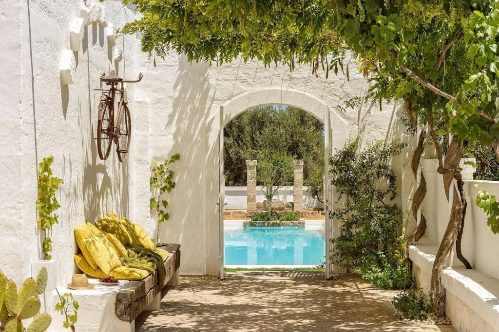 une arche menant à une piscine avec un vélo dans l'établissement Masseria Narducci, à Montalbano