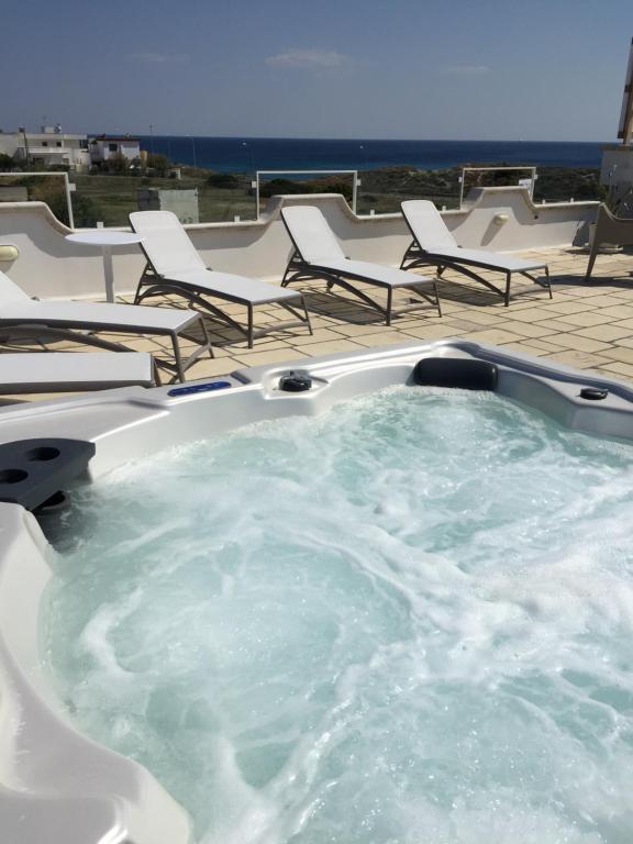 a jacuzzi tub with chairs and the ocean in the background at Magia del Salento in Torre San Giovanni Ugento