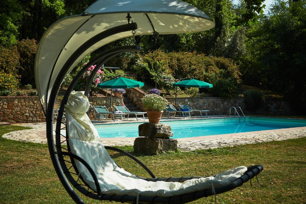 uma estátua de uma mulher sentada numa cadeira ao lado de uma piscina em La Loggetta - Chianti apartments em Gaiole in Chianti