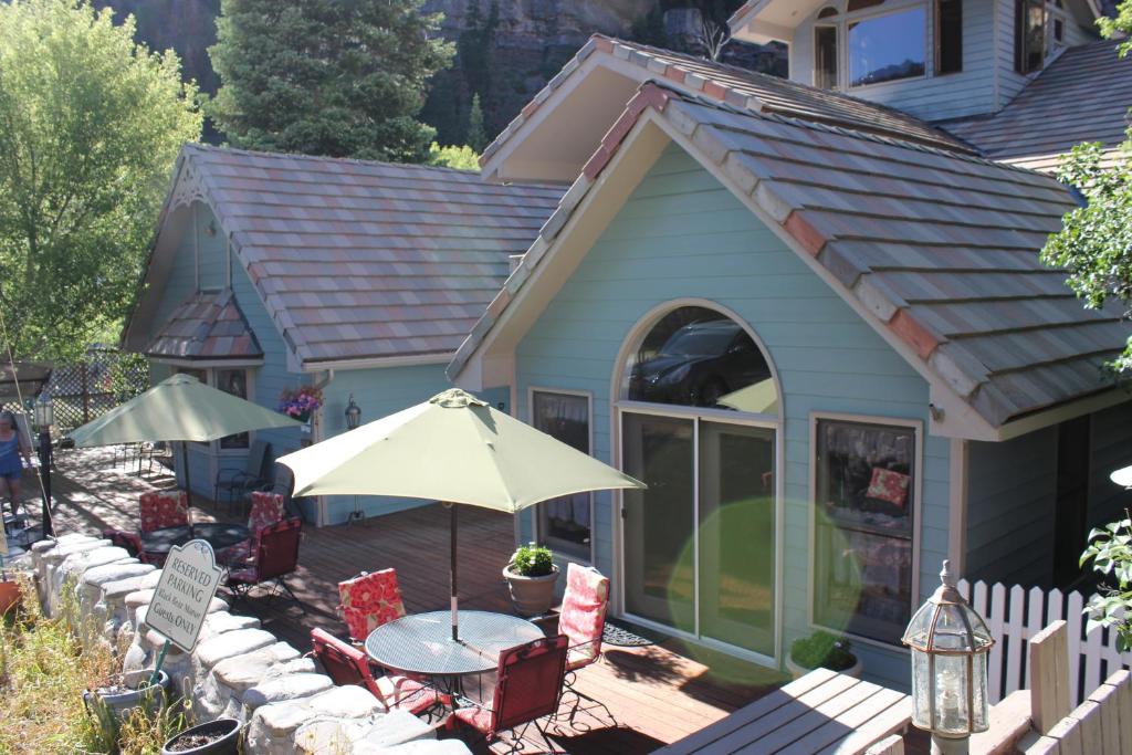 ein Haus mit einem Tisch, Stühlen und einem Sonnenschirm in der Unterkunft Black Bear Manor in Ouray