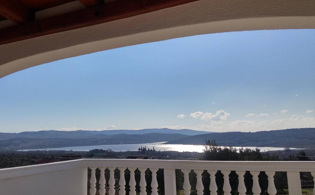 a balcony with a view of the water and mountains at The Garden of Elaïs in Šibenik