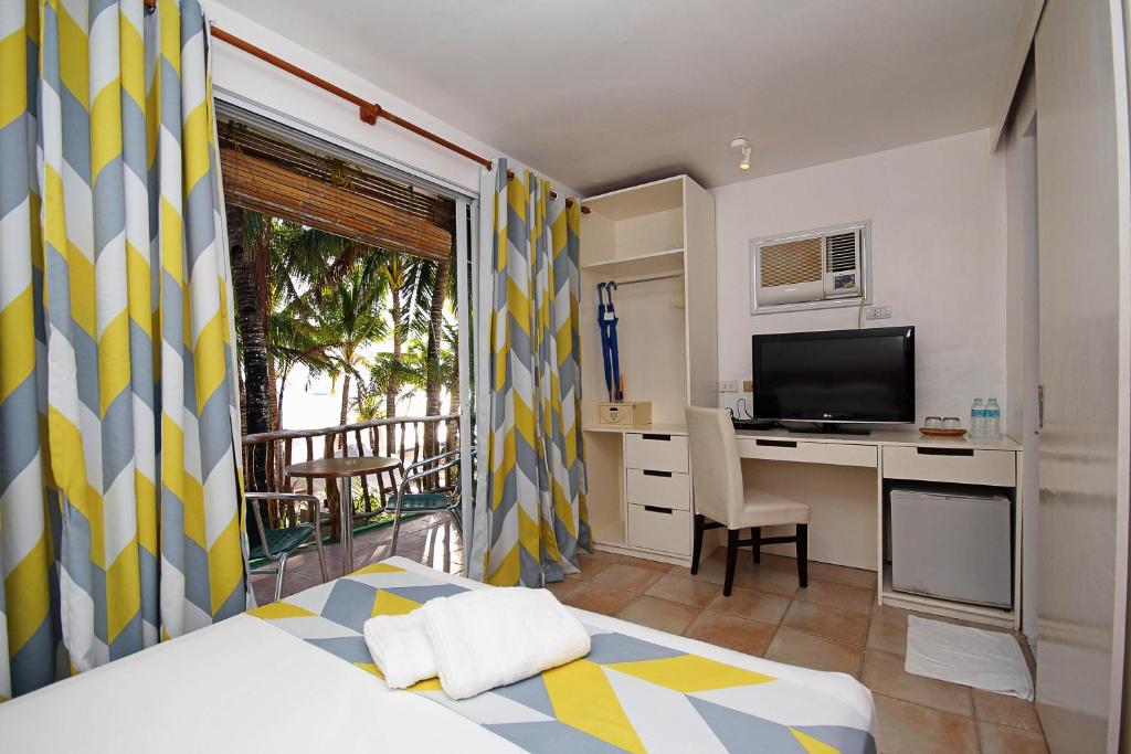 a bedroom with a bed and a desk with a television at Bluewaves Beach House in Boracay