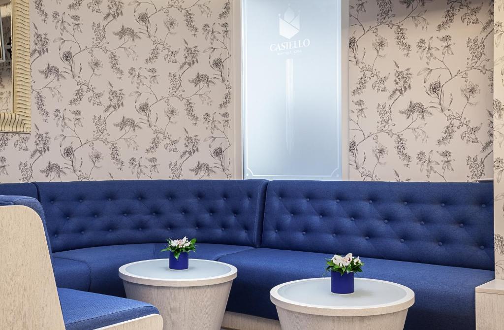 a blue couch in a living room with two tables at Castello Boutique Hotel in Čačak