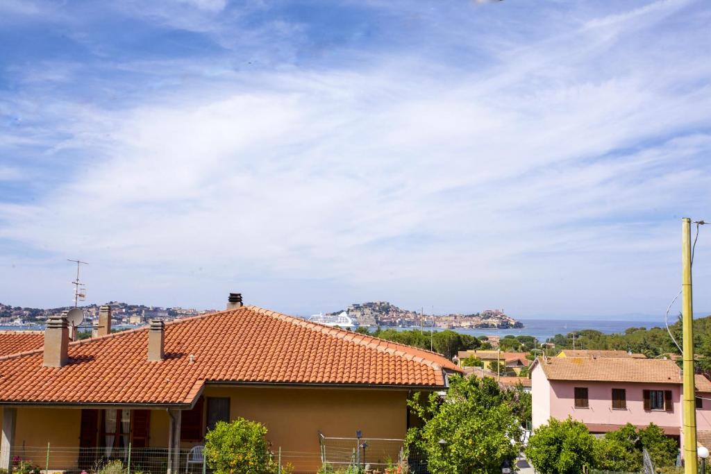 una casa con un techo rojo y un cielo nublado en Appartamento Le Conchiglie - Goelba, en Portoferraio