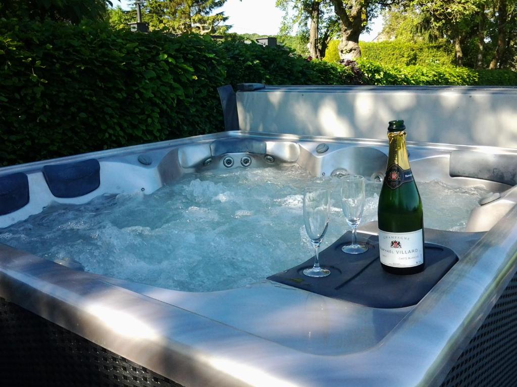 a hot tub with a bottle of wine and two glasses at B&amp;B La Buissonniere in Xhoris