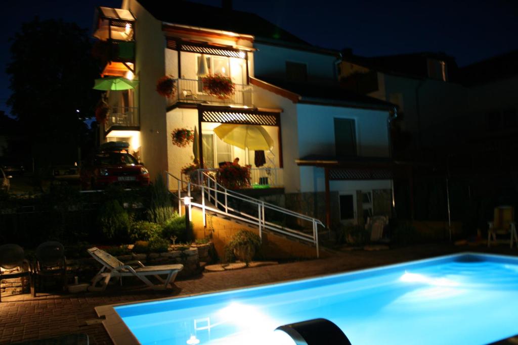 a swimming pool in front of a house at night at Apart Hévízi Ház in Hévíz