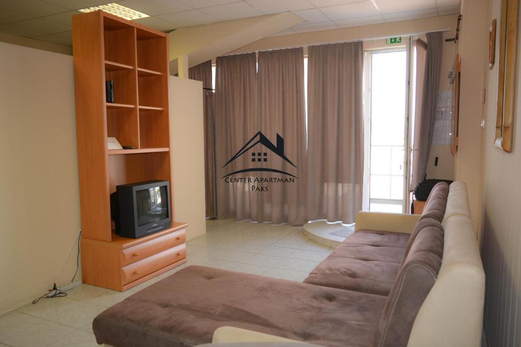 a living room with a couch and a tv at Center Apartman - Paks in Paks