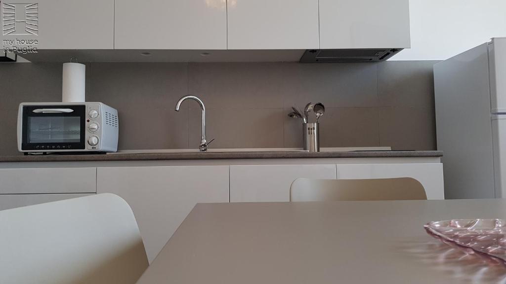 a white kitchen with a microwave and a table at Case Vacanza Marzano in Monopoli