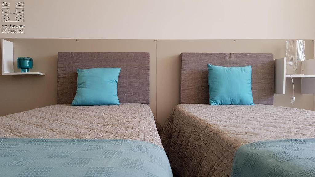 two beds with blue pillows in a bedroom at Case Vacanza Marzano in Monopoli