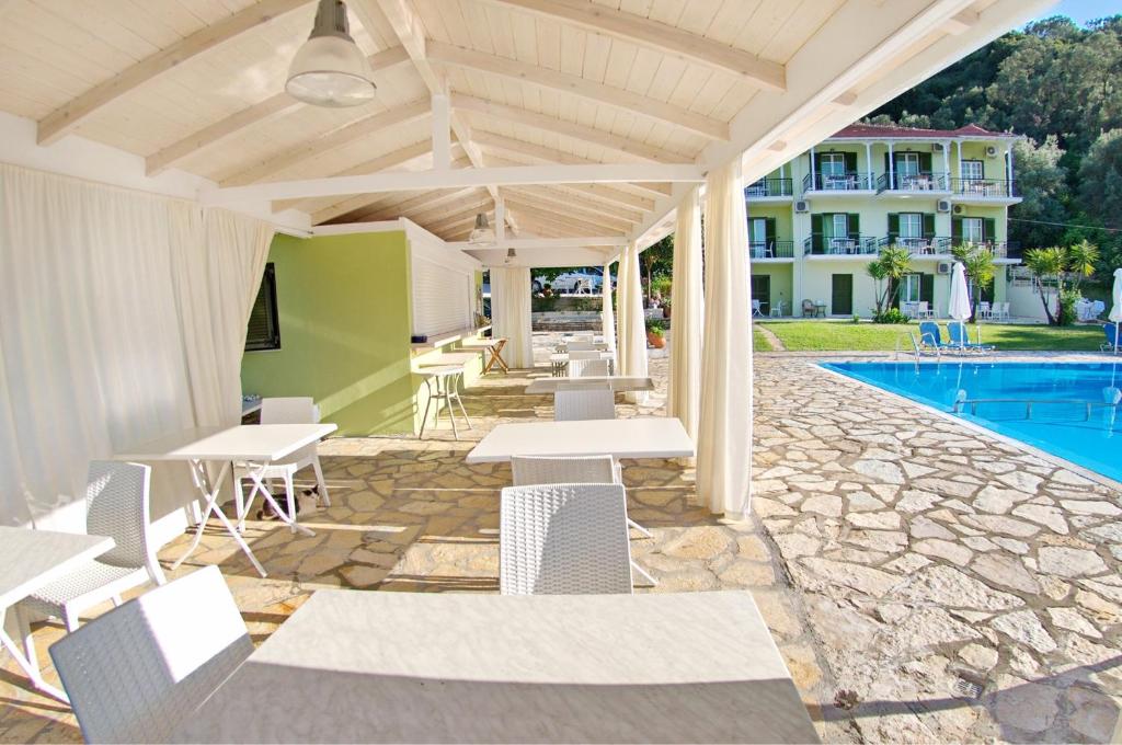 patio ze stołami i krzesłami przy basenie w obiekcie Vliho Bay Suites & Apartments w mieście Yénion
