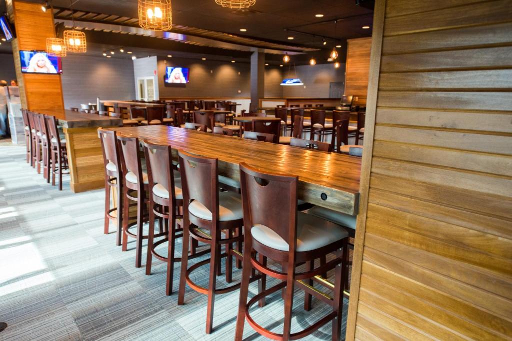 eine Bar in einem Restaurant mit Holztischen und -stühlen in der Unterkunft Hope Hotel and Richard C. Holbrooke Conference Center in Fairborn