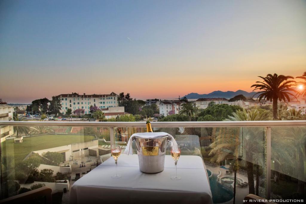 a table with two glasses of wine on a balcony at Hotel Cannes Montfleury in Cannes